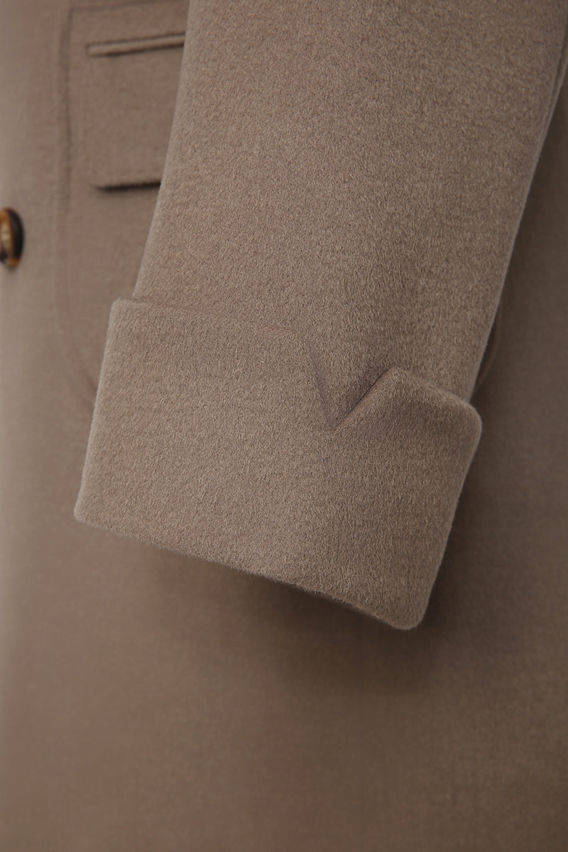 Close-up of a beige coat with a pocket and button detail