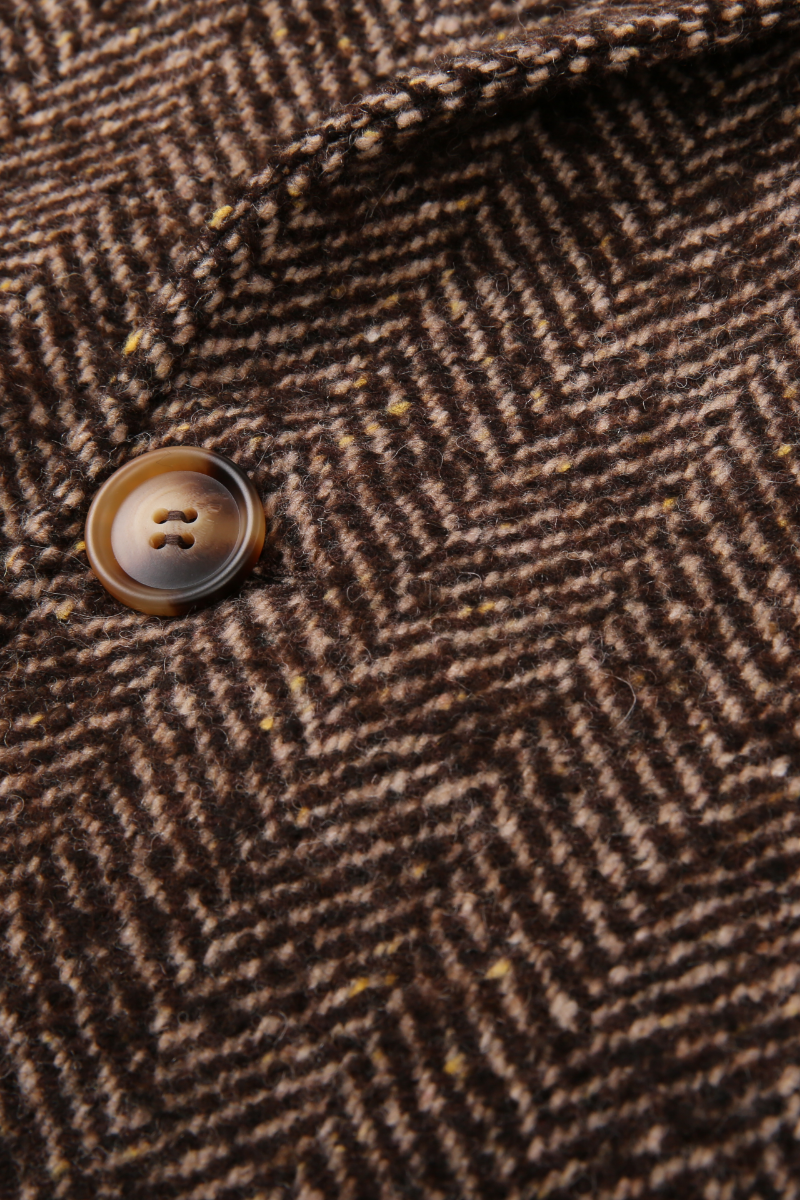 Close-up of a brown herringbone patterned fabric with a button. business formal wear for women