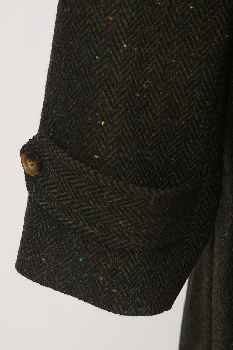 Close-up of a textured fabric pocket on a dark coat with a white background