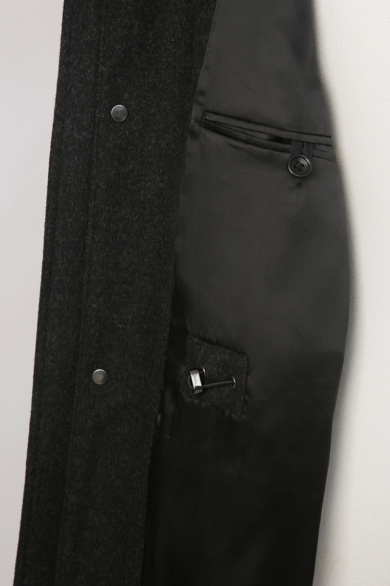 Close-up of a dark gray coat with buttons and zippers on a white background