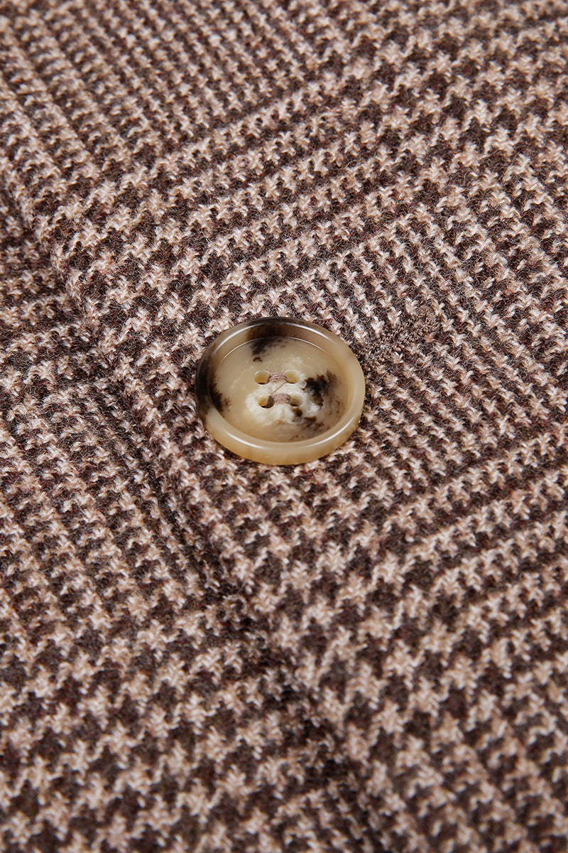 Close-up of a button on a brown and beige houndstooth patterned fabric.