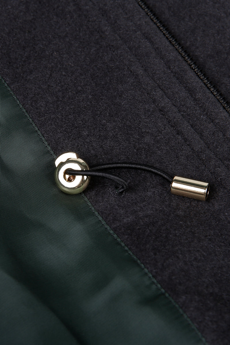 Close-up of a black and green fabric with a zipper and metal pull.