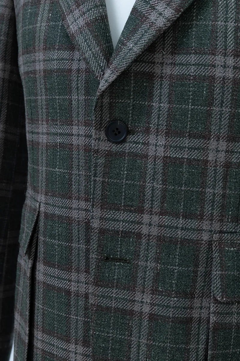 Close-up of a green and brown plaid coat with a button. custom suits miami