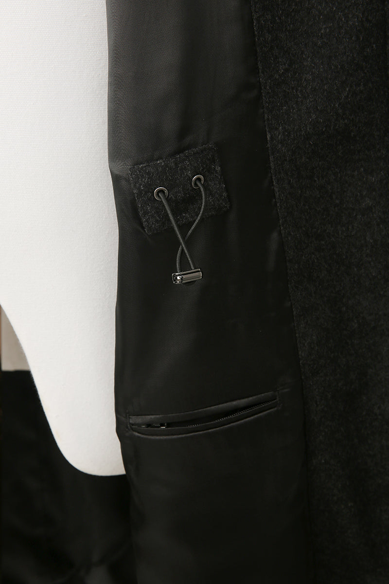 Close-up of a black coat with a textured pocket detail on a white background