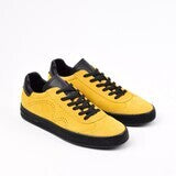 A pair of yellow lace-up sneakers with black suede accents and a rubber outsole.