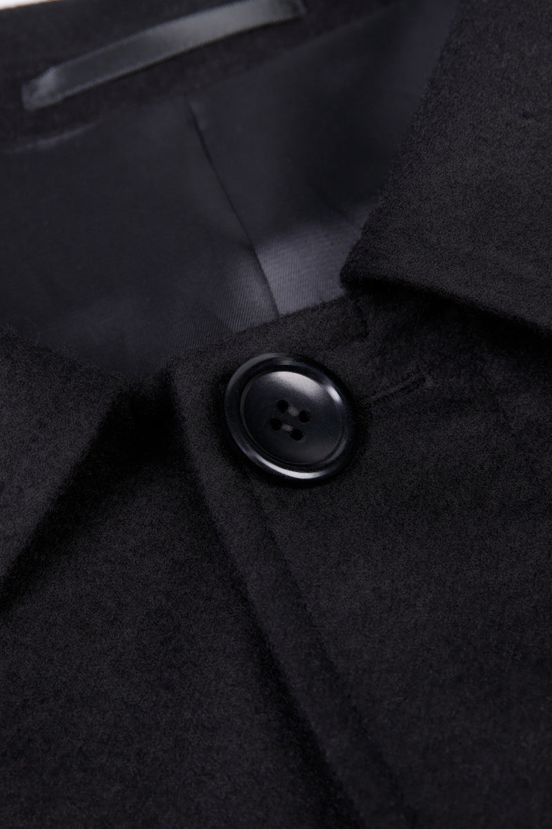 Close-up of a black coat with a button on a dark background
